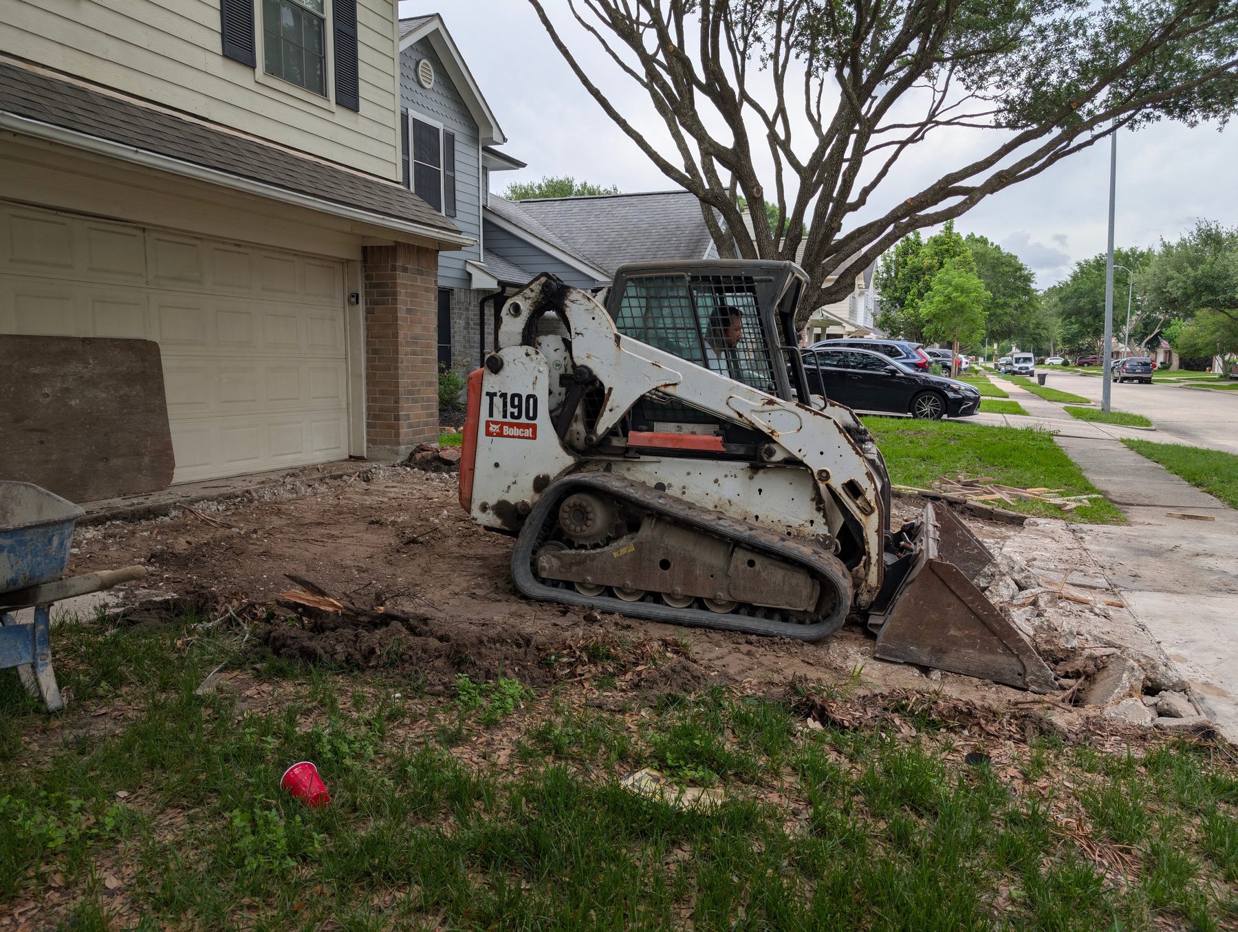 Skid steer removing old driveway concrete at a Houston home