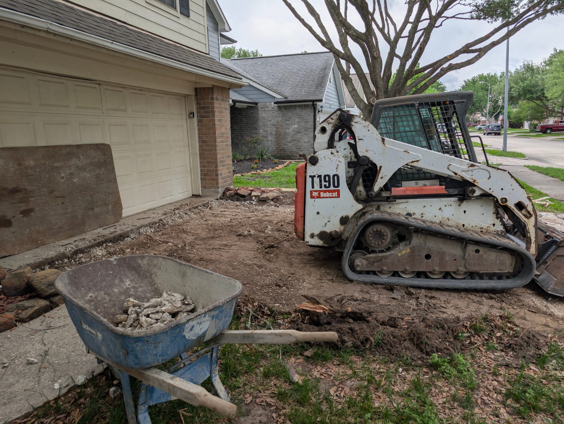 Bobcat and wheelbarrow during a Houston driveway tear-out