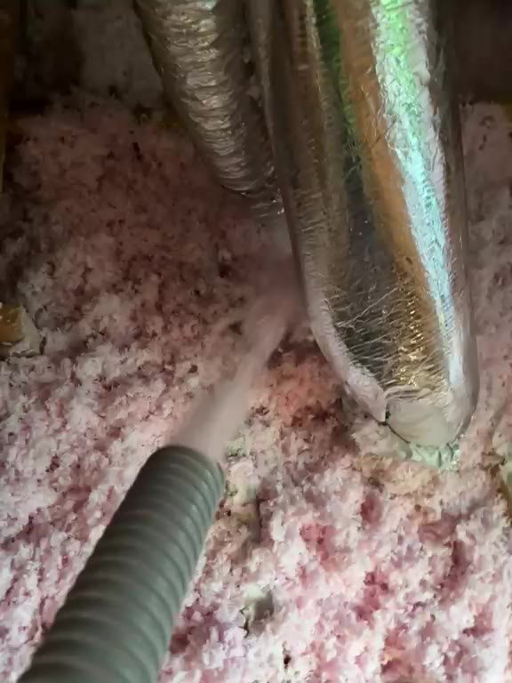 Fresh blown-in fiberglass packed around HVAC ductwork in a Houston attic