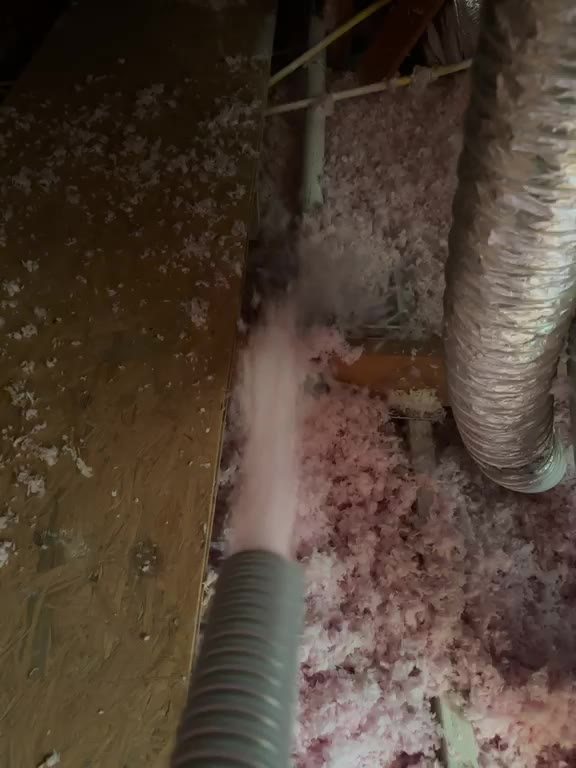 Insulation hose packing blown-in fiberglass next to a flexible duct