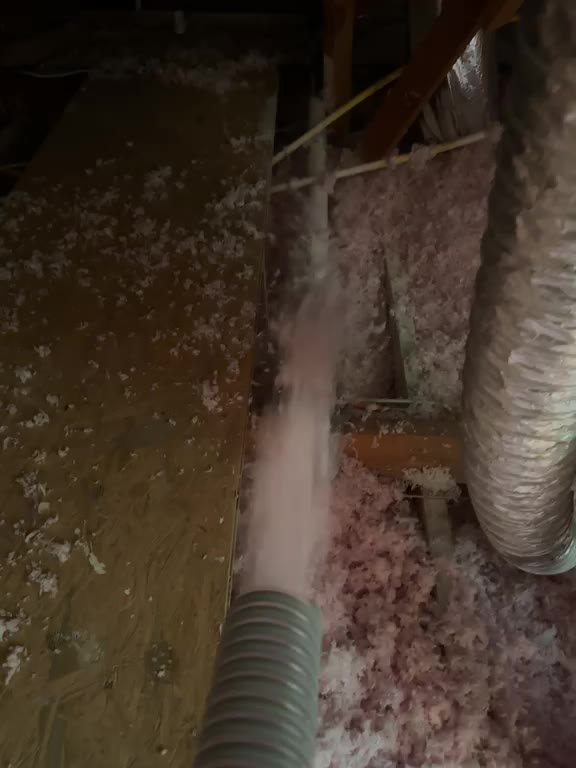 Blowing hose filling joist bays with fiberglass insulation