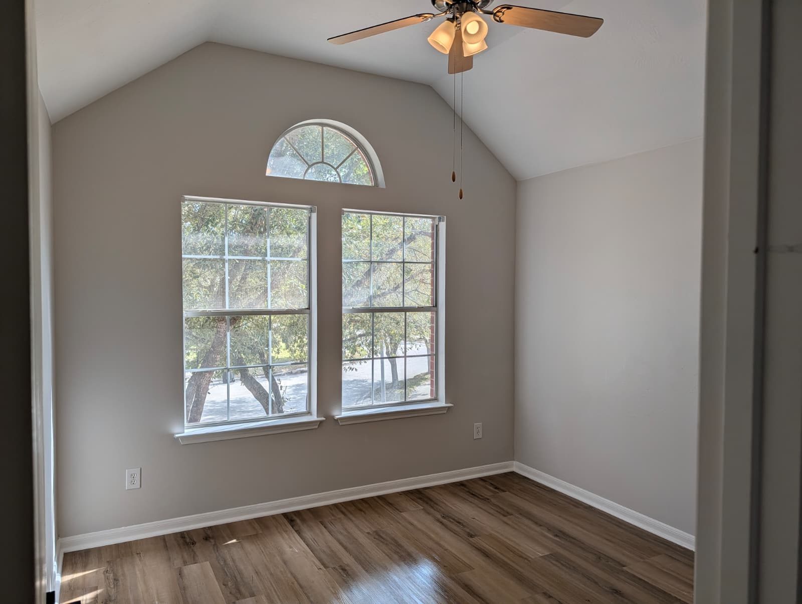 Finished bedroom with an arched window and ceiling fan