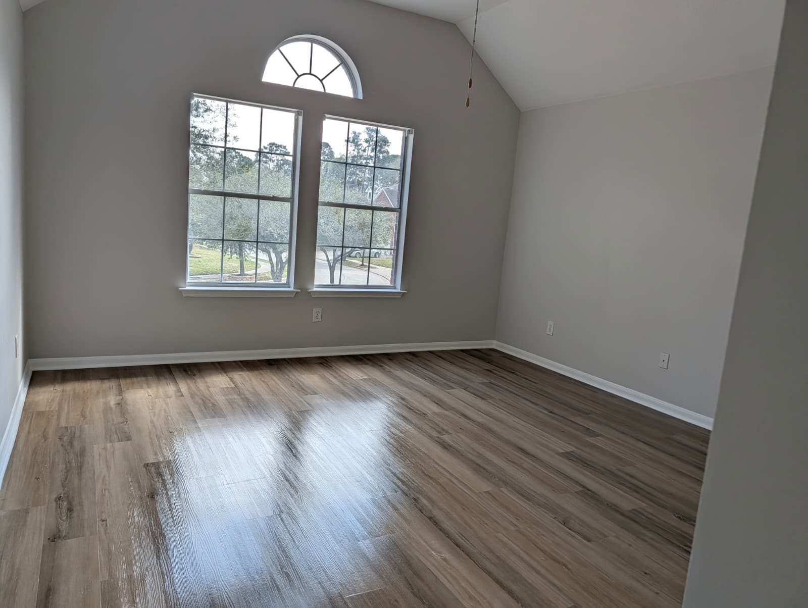 Same bedroom after remodel with new wood-look flooring and fresh paint