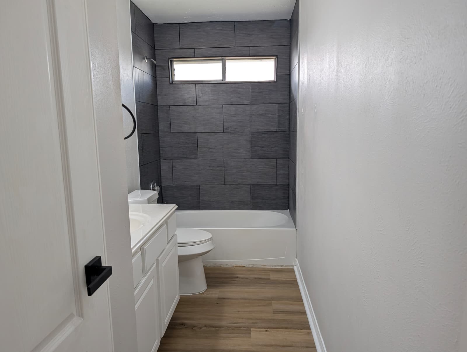 Bathroom after remodel with a new vanity, toilet, and tiled tub