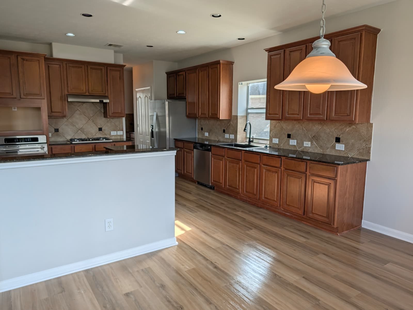 Kitchen after remodel with wood cabinets, dark counters, and new floors