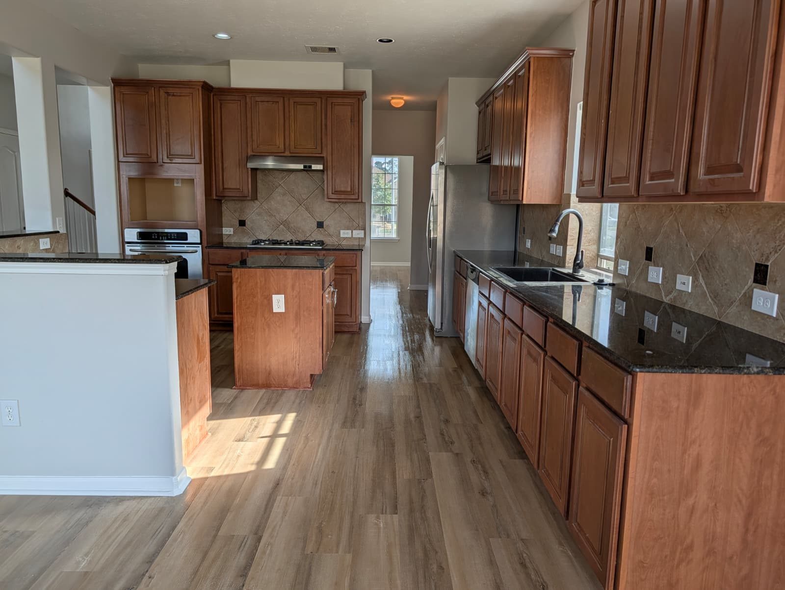 Kitchen sink run after remodel with granite counters and wood cabinets