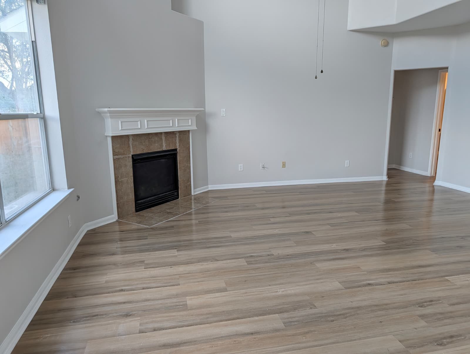 Finished living room with new wood-look floors and a tiled fireplace