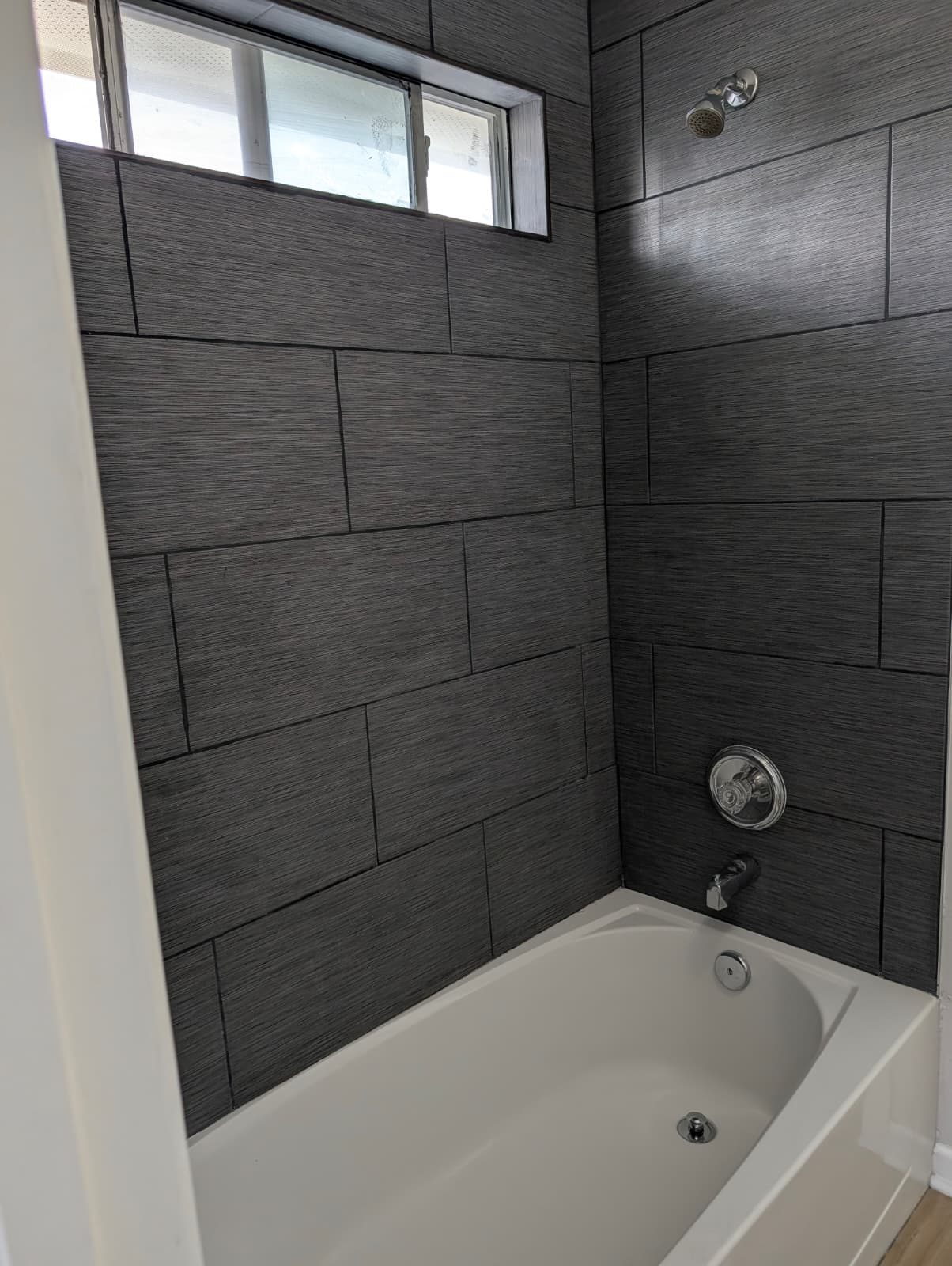 Tub and shower with gray wood-look tile after the remodel