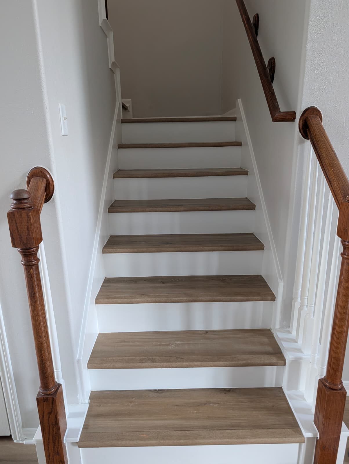 Stairs after remodel with wood treads, white risers, and a wood handrail