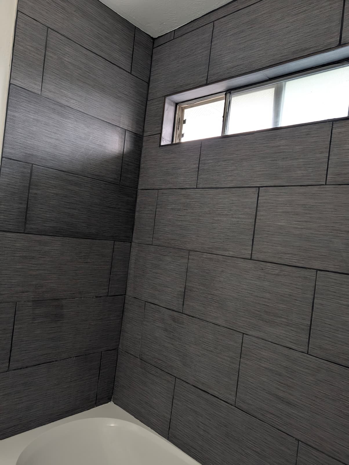 Gray tile surround and window above the tub
