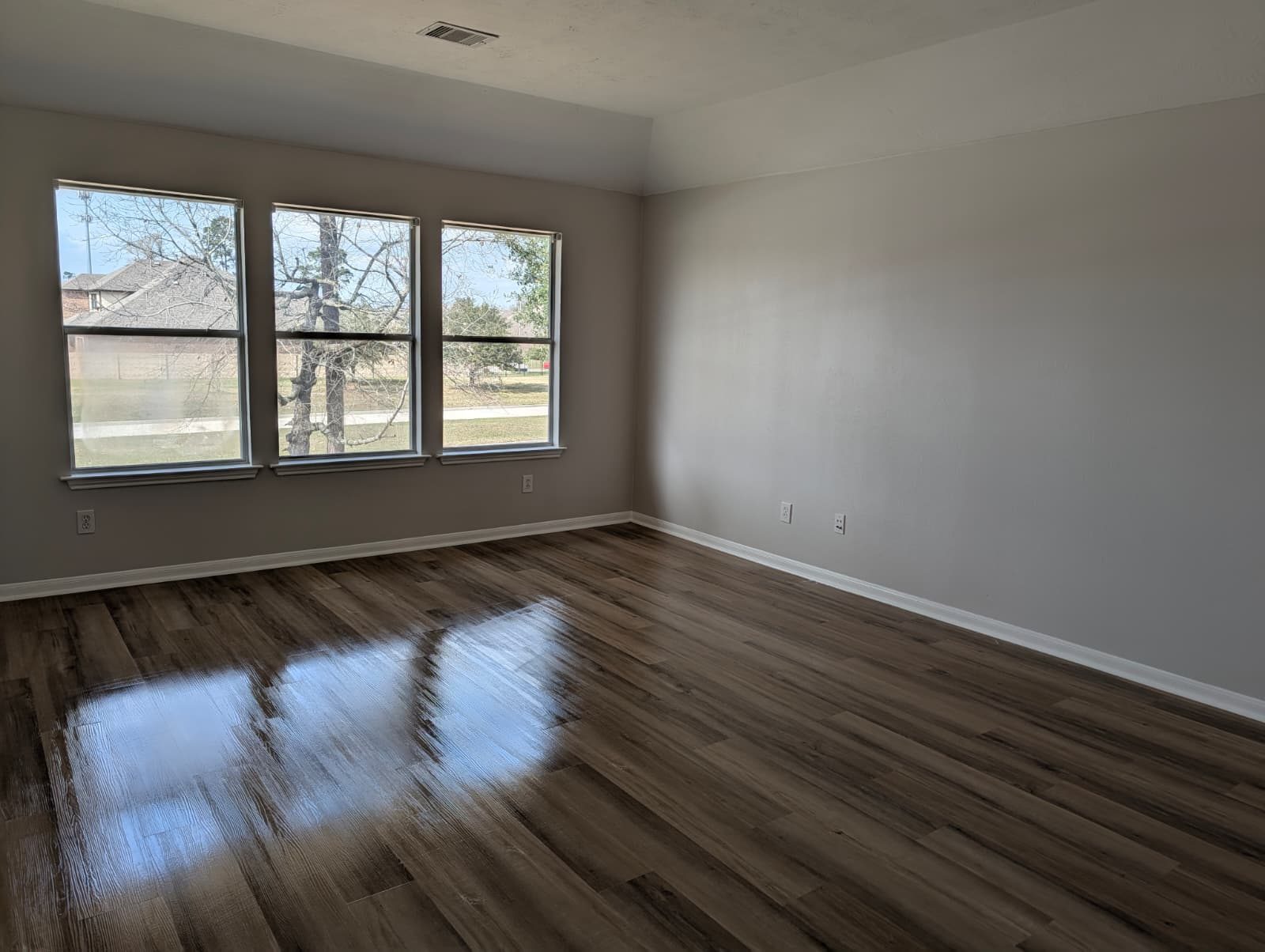 Bedroom with three windows after new floors replaced the old carpet