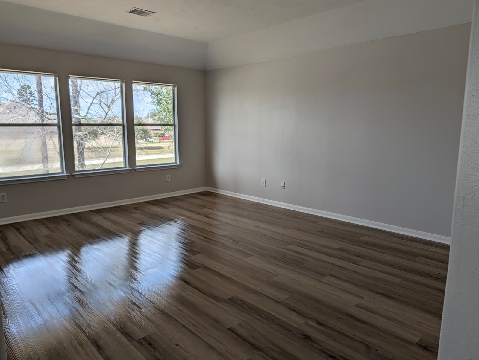 Same three-window bedroom after paint and flooring