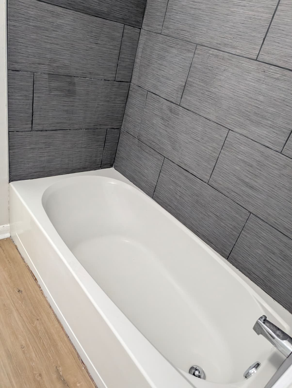 New white tub with a gray tile surround