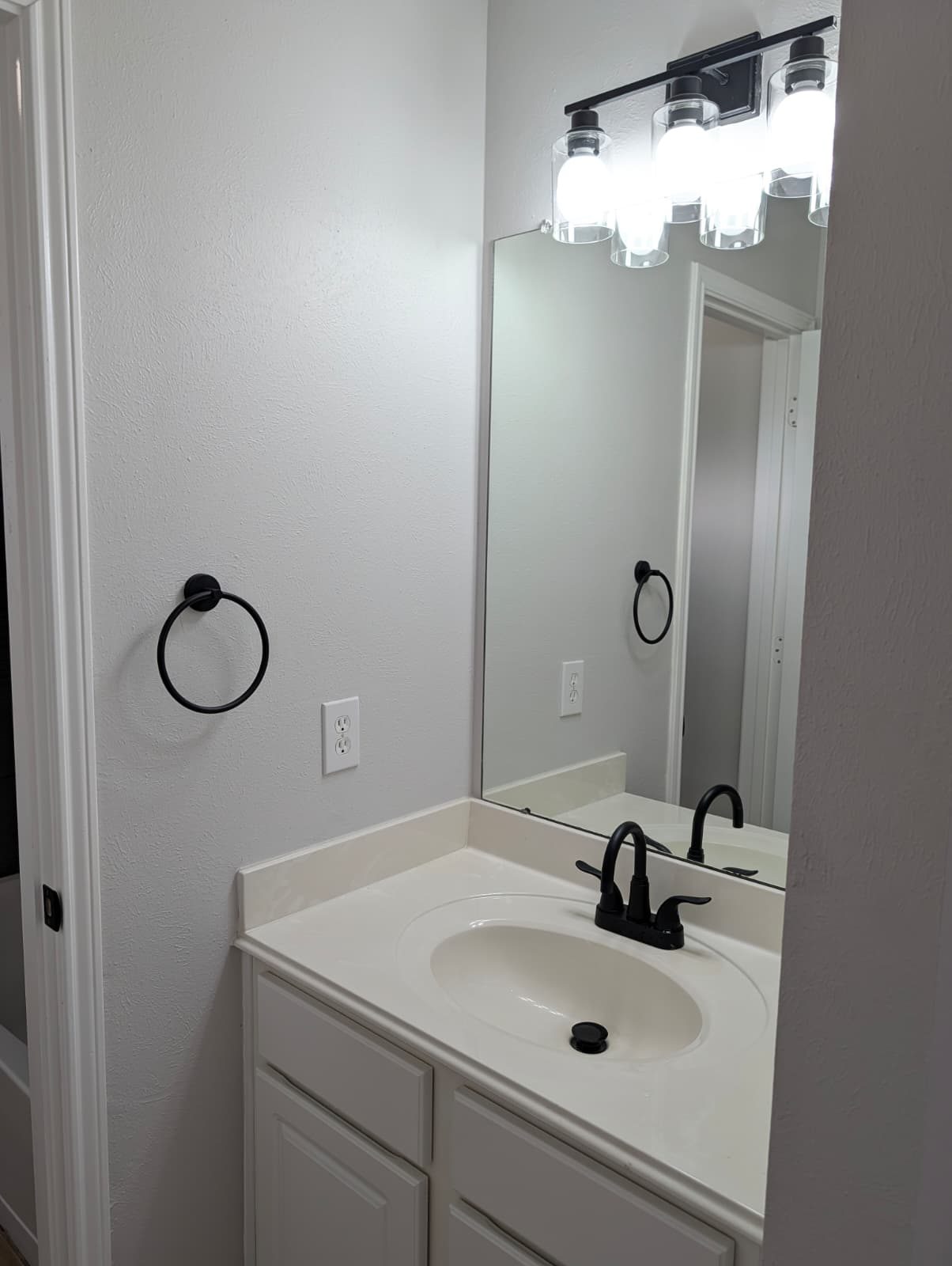 New bathroom vanity with a black faucet and light bar