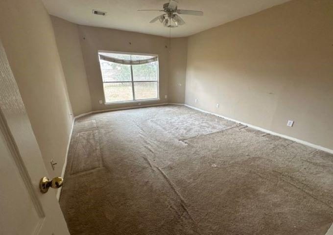 Bedroom with worn carpet and a ceiling fan before the remodel